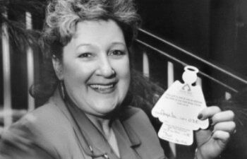 Photo of Mary Kay Beard, the founder of Angel Tree, holding an angel-shaped gift tag